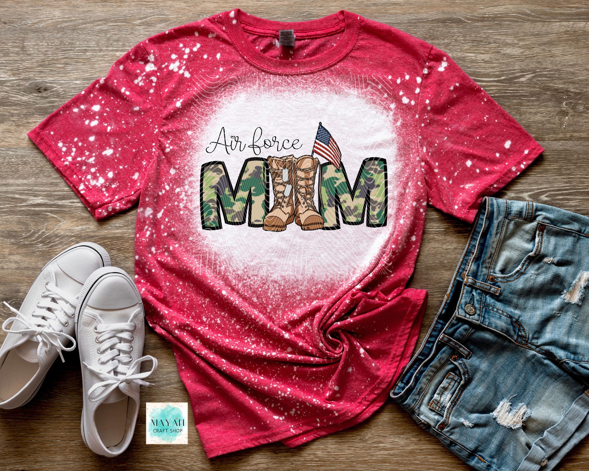 Red t-shirt with military mom design on a wooden surface with white sneakers and denim shorts.