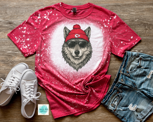 Red t-shirt with wolf graphic, white sneakers, and denim shorts on a wooden surface