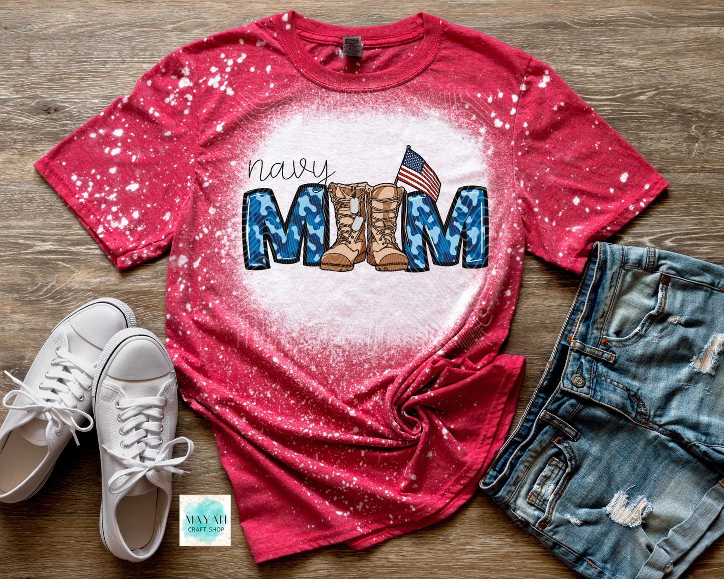 Red t-shirt with military mom text and boots design, paired with white sneakers and denim shorts on a wooden surface.