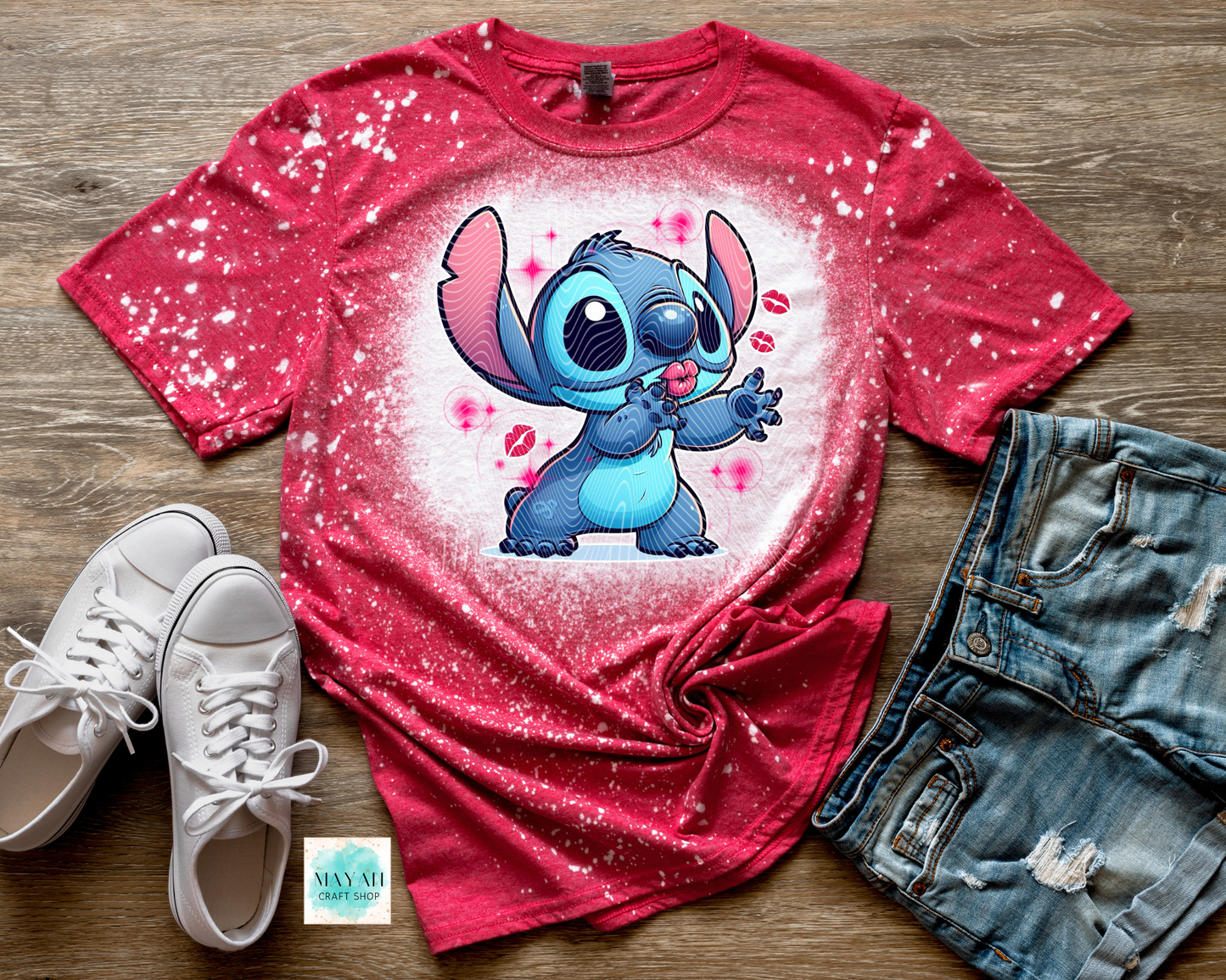 Red t-shirt with cartoon character design on a wooden surface with white sneakers and denim shorts.