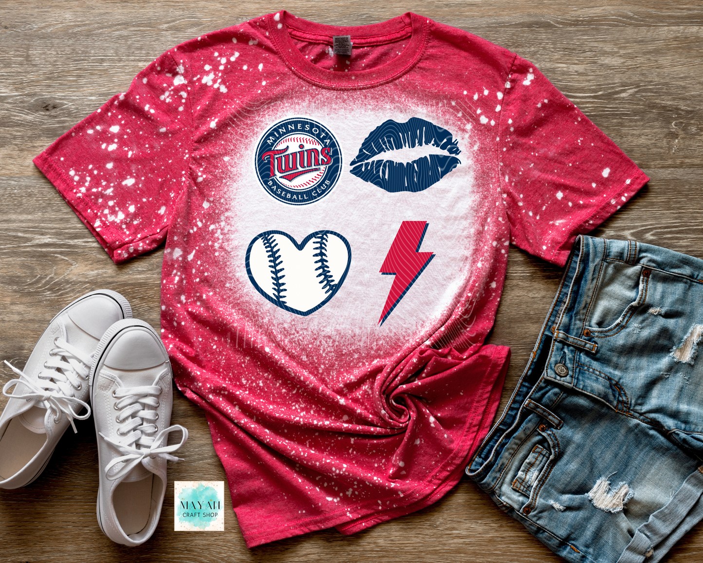 Red t-shirt with sports-themed graphics on a wooden surface with white sneakers and denim shorts.