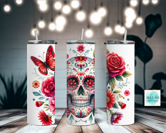 Three tumblers with floral and skull designs on a wooden surface with blurred lights in the background.