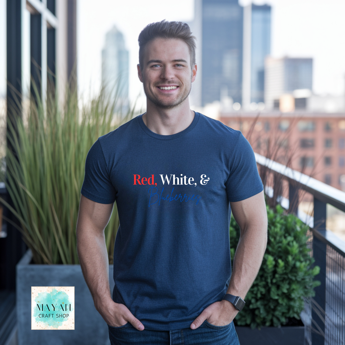 Man wearing a navy blue t-shirt with text, standing on a balcony with cityscape background