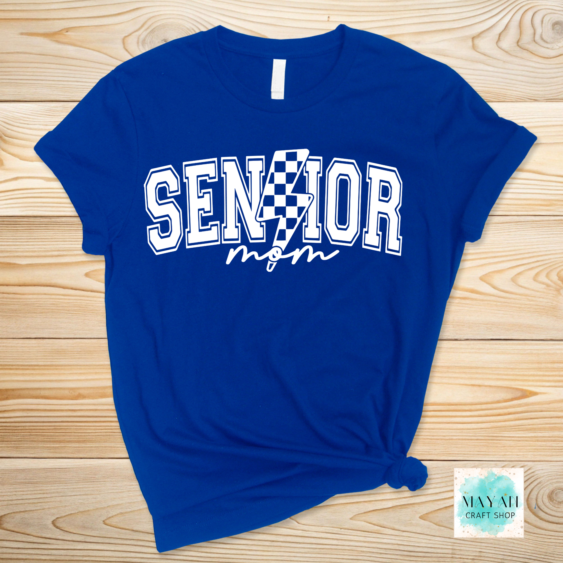 Blue t-shirt with 'Senior Mom' text on a wooden surface, featuring a checkered design.