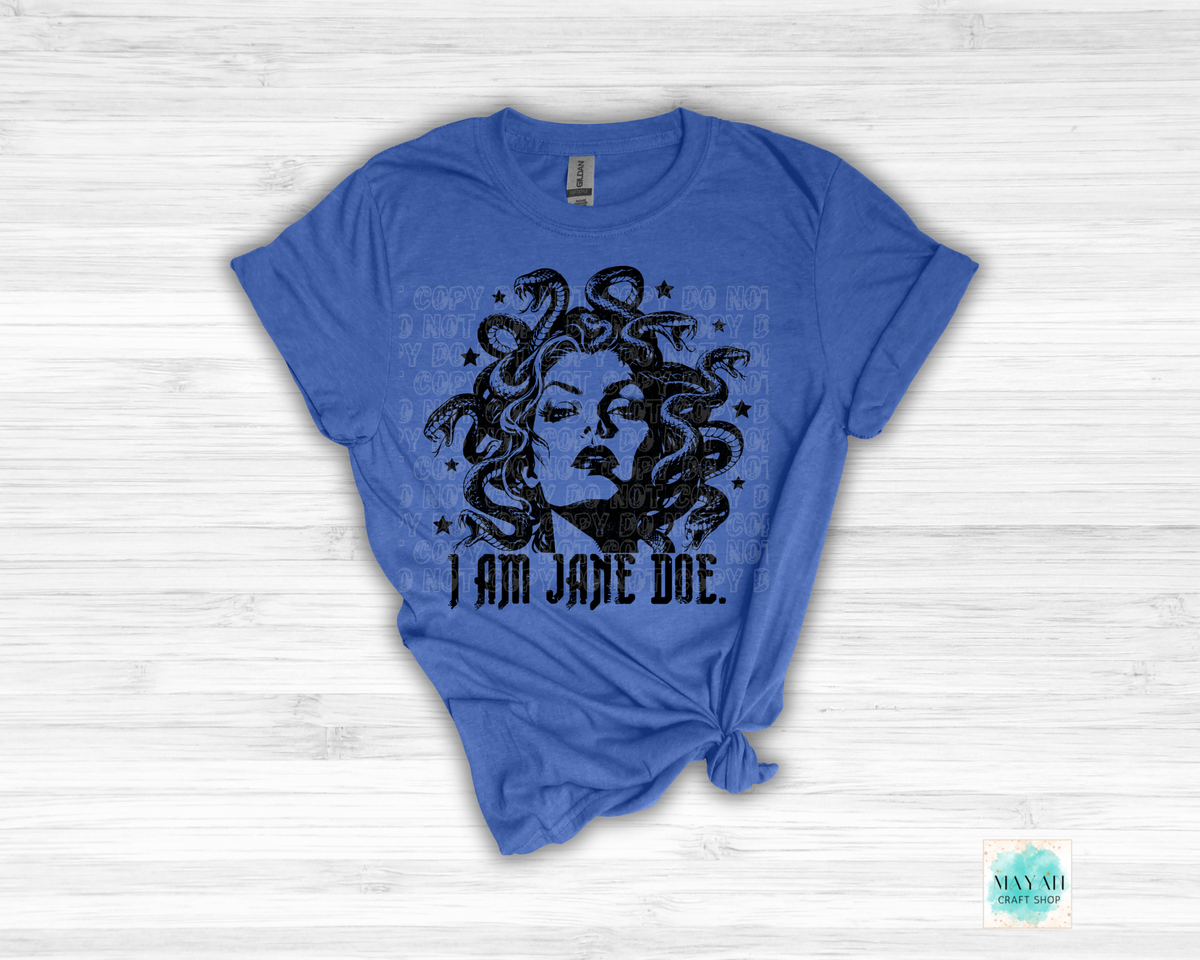 A heather royal blue short-sleeve t-shirt with a distressed black graphic of Medusa's face and hair, with the text 'I AM JANE DOE.' printed below.