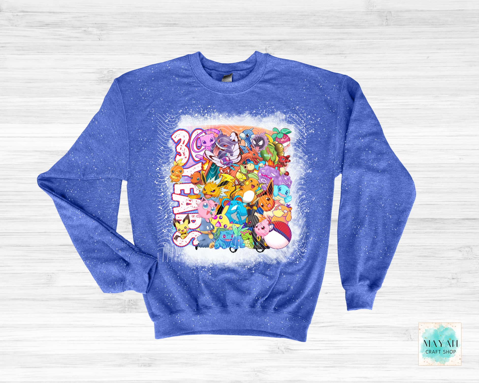 Blue sweatshirt with colorful graphic design on a white wooden background