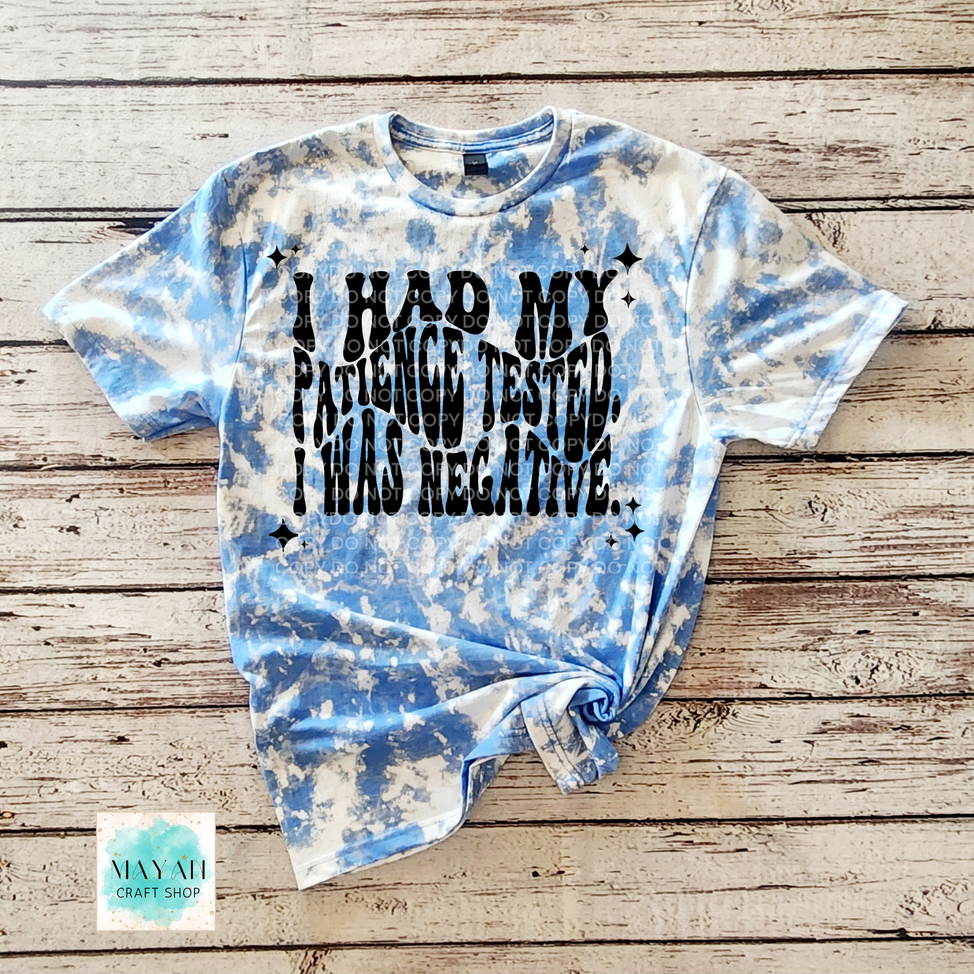 Tie-dye t-shirt with text on a wooden surface, featuring the brand 'Mayan Craft Shop'.