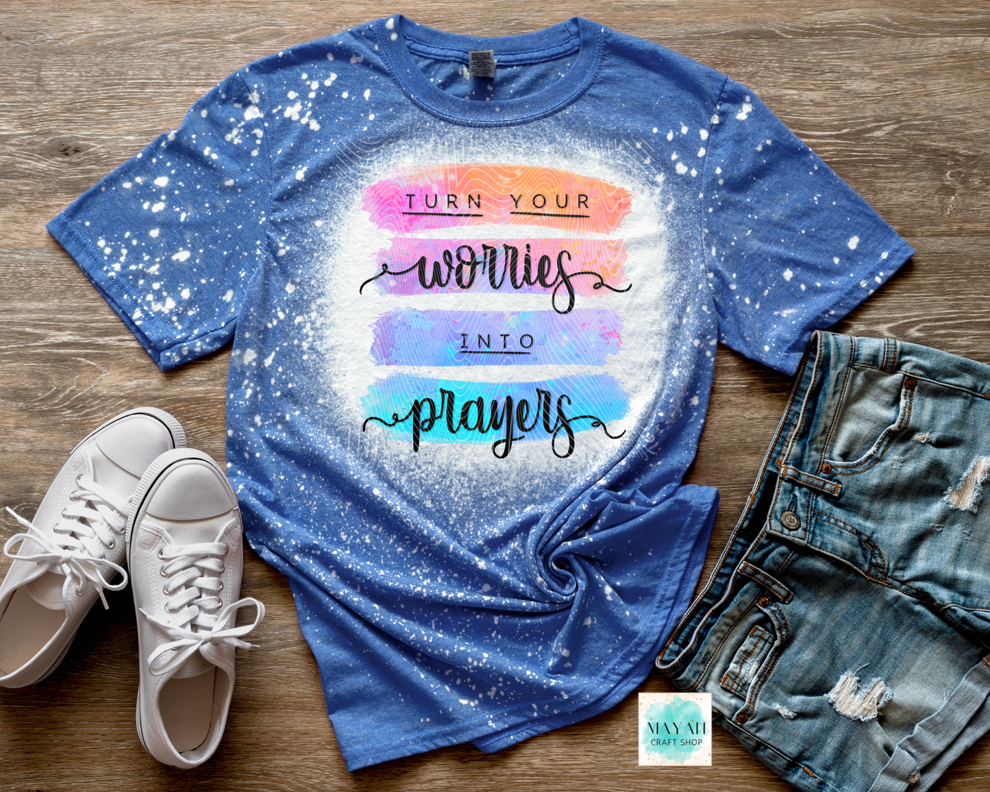 Blue t-shirt with motivational quote on a wooden surface with shoes and jeans.