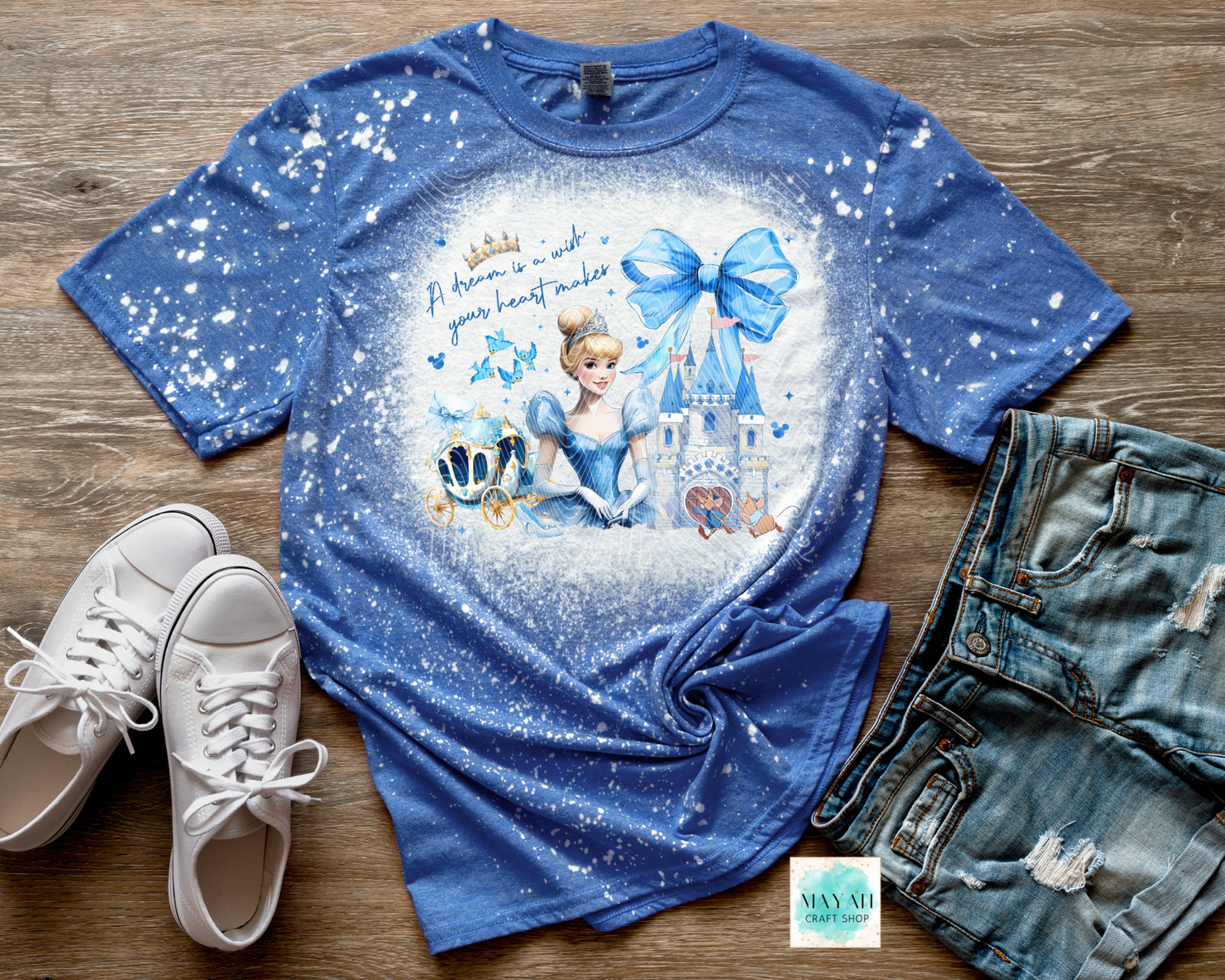 Blue t-shirt with princess design on a wooden surface with shoes and shorts.