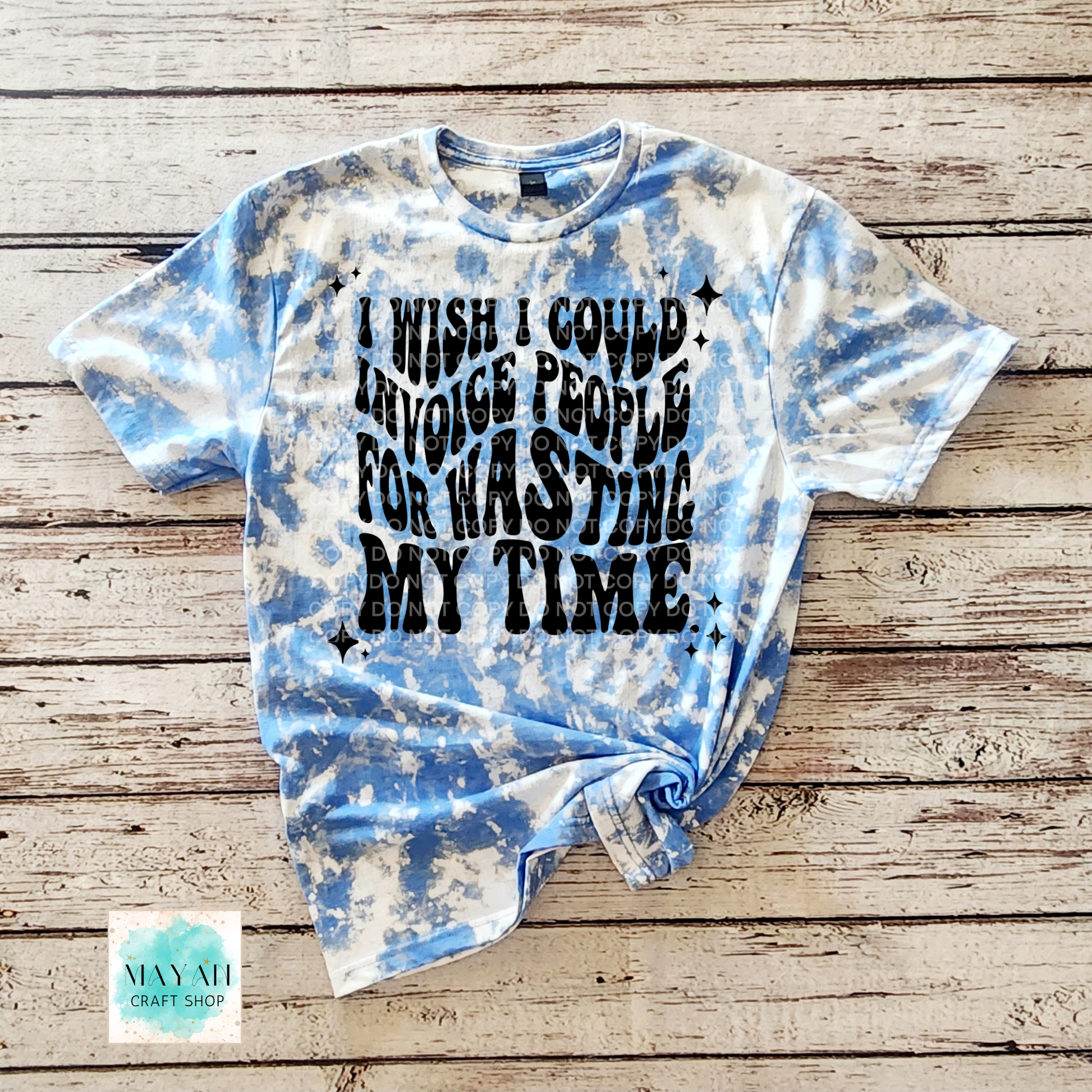 Tie-dye t-shirt with text on a wooden surface, featuring the brand 'Mayan Craft Shop'.