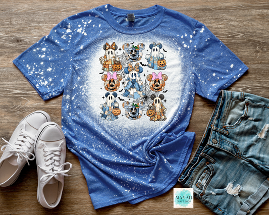 Blue t-shirt with cartoon character design on a wooden surface with white sneakers and denim shorts.