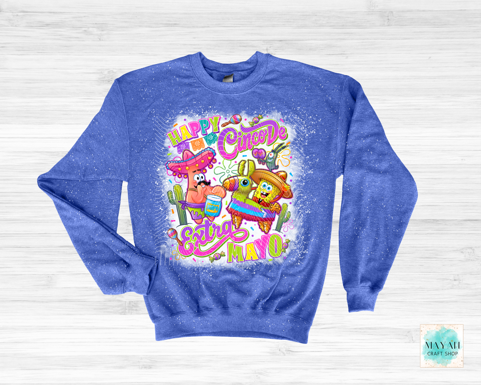 Blue sweatshirt with colorful 'Happy Cinco de Mayo' design on a white wooden background