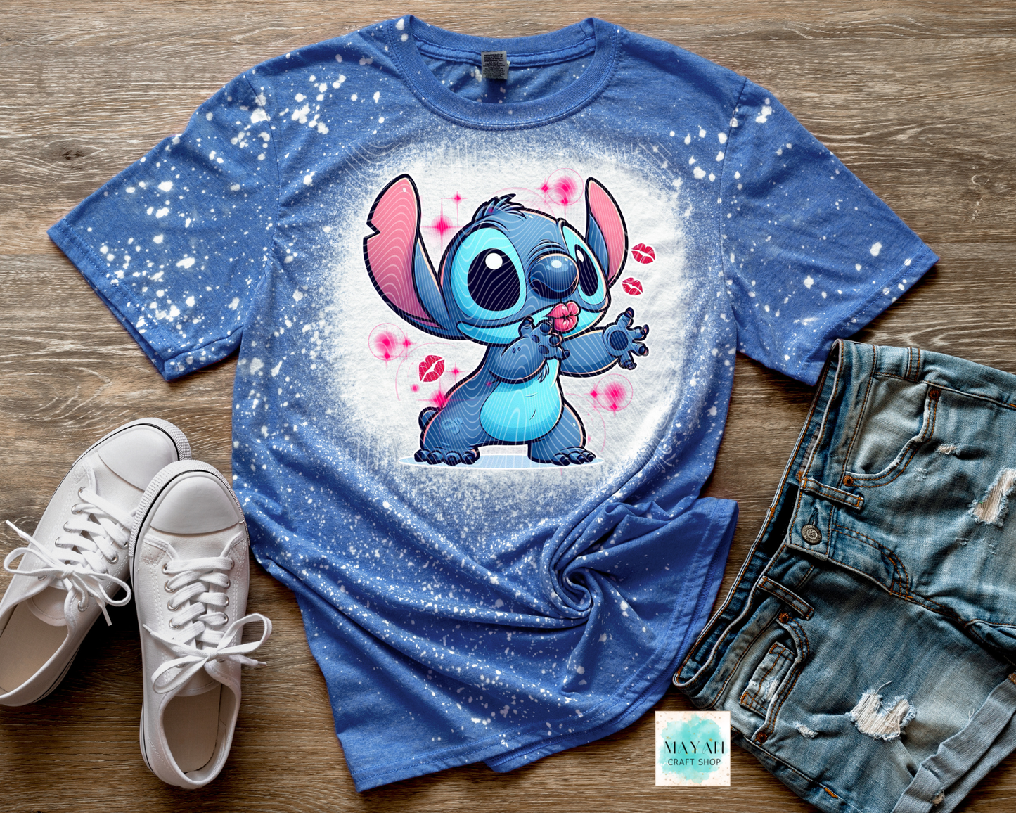 Blue t-shirt with cartoon character, white sneakers, and denim shorts on a wooden surface
