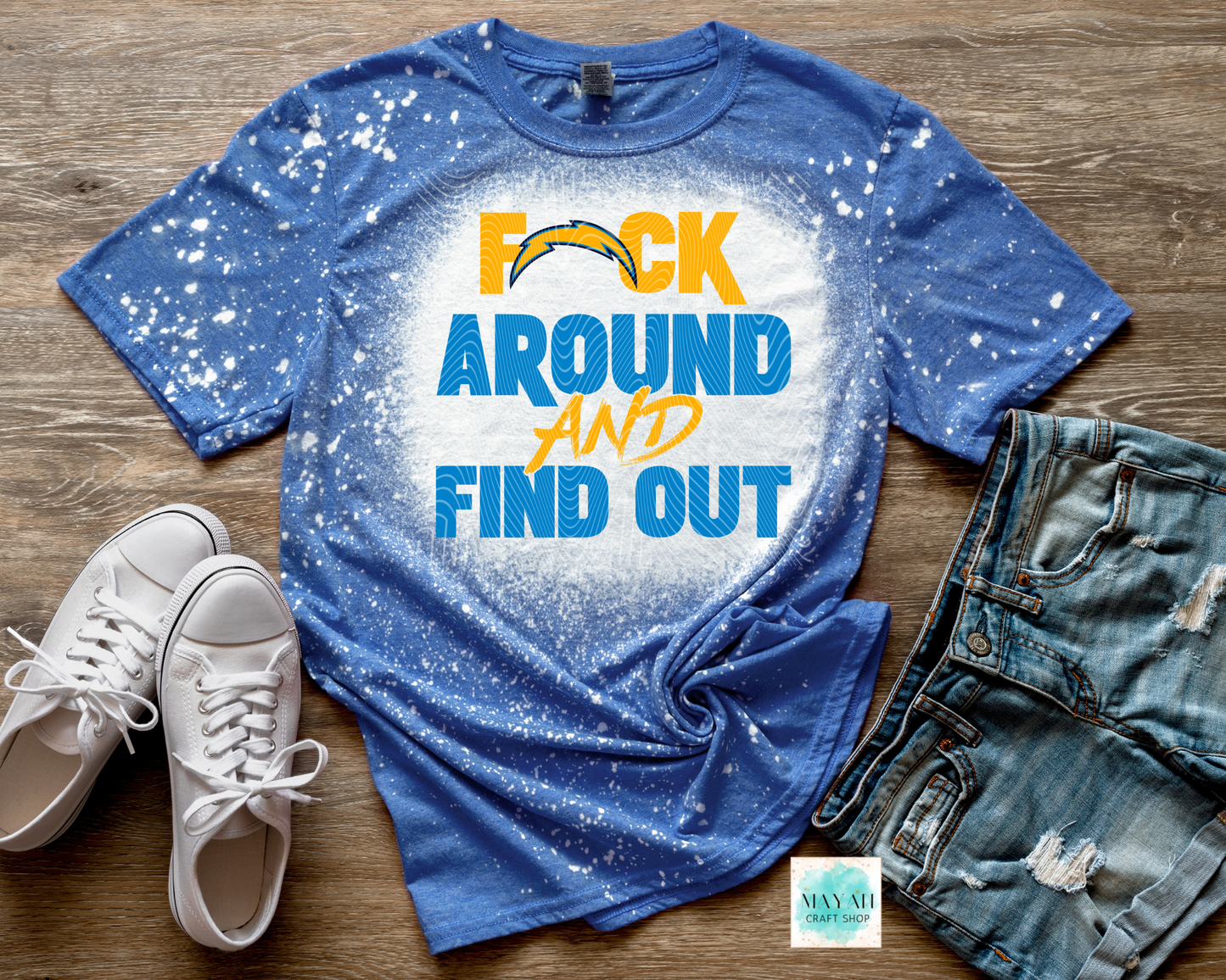 Blue t-shirt with text and sports team logo on a wooden surface with shoes and shorts.