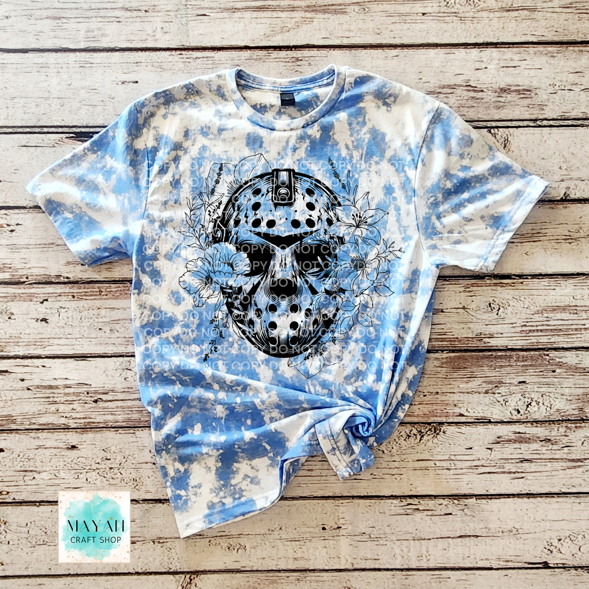 Tie-dye t-shirt with a skull design on a wooden surface, featuring the brand.
