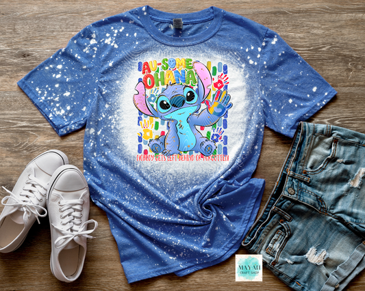 Blue t-shirt with cartoon character and text on a wooden surface with shoes and shorts.