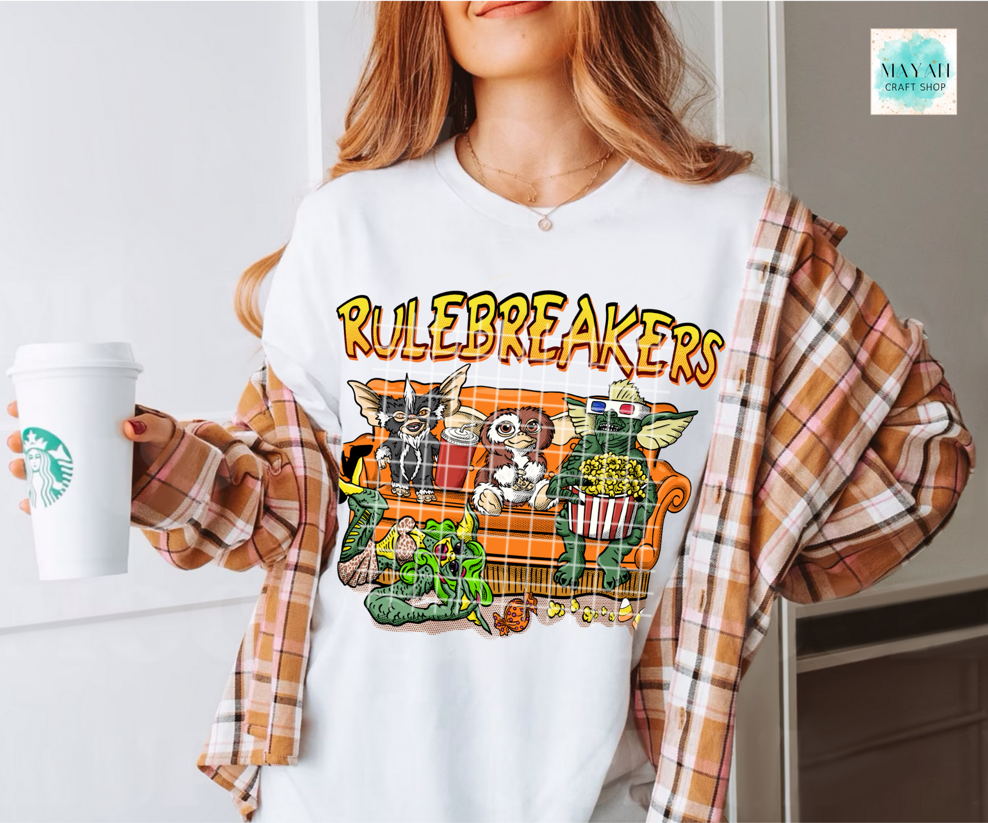 Person wearing a white t-shirt with 'Rulebreakers' graphic design, holding a coffee cup.