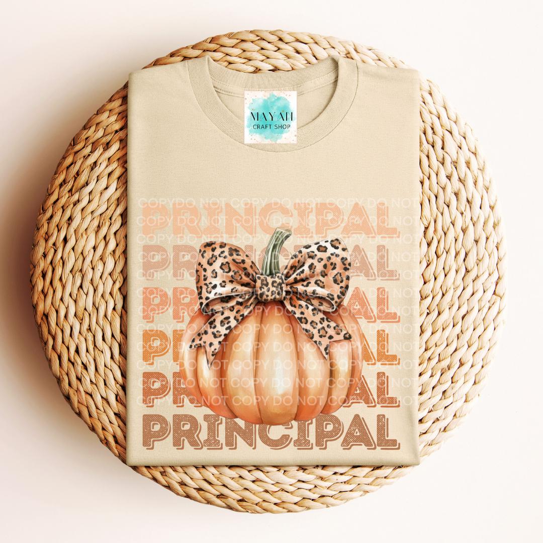 Beige t-shirt with 'PRINCIPAL' text and pumpkin design on a woven surface