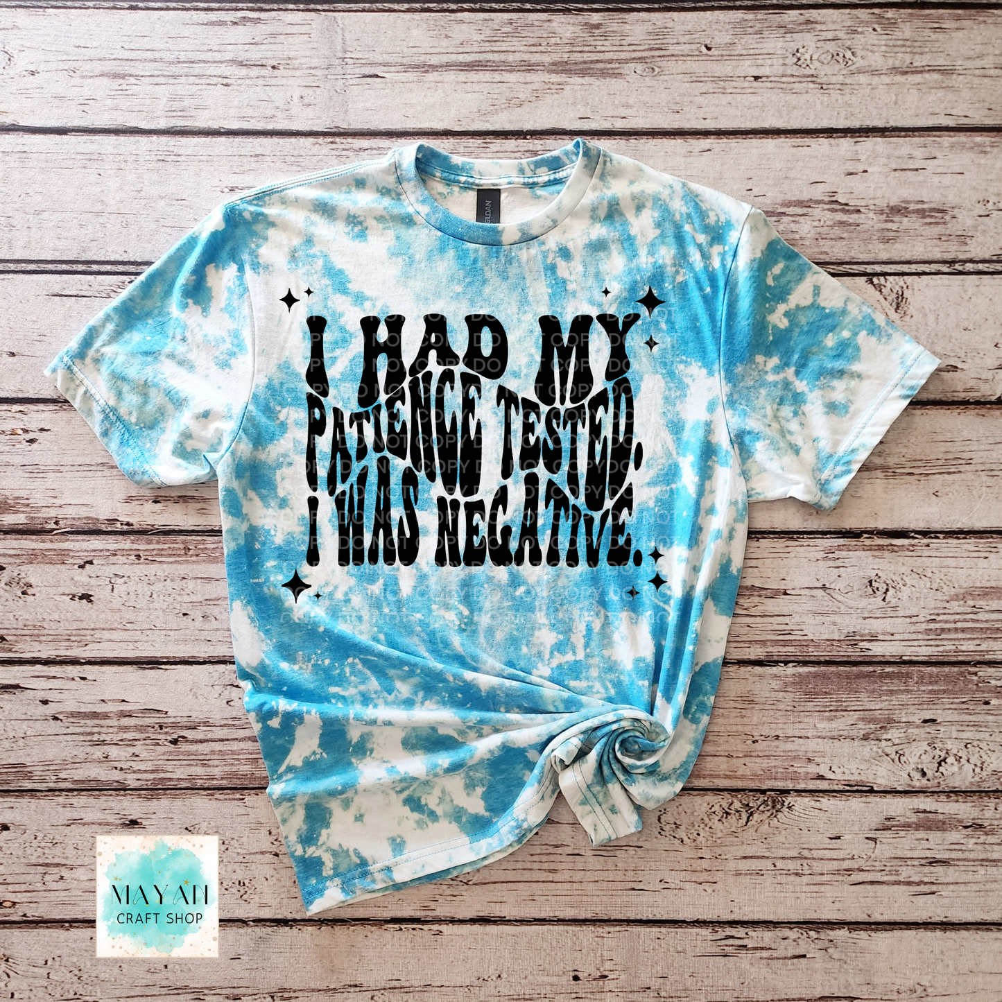 Tie-dye t-shirt with text on a wooden surface, featuring the brand 'Mayan Craft Shop'.