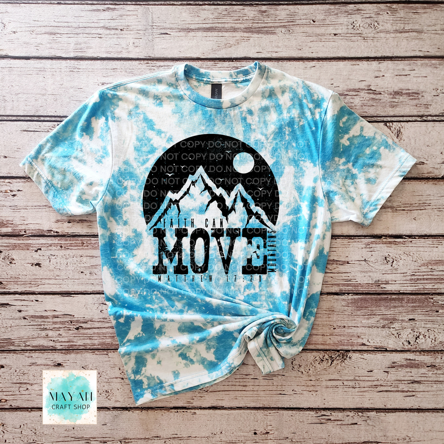 Tie-dye t-shirt with mountain graphic and 'MOVE' text on a wooden surface