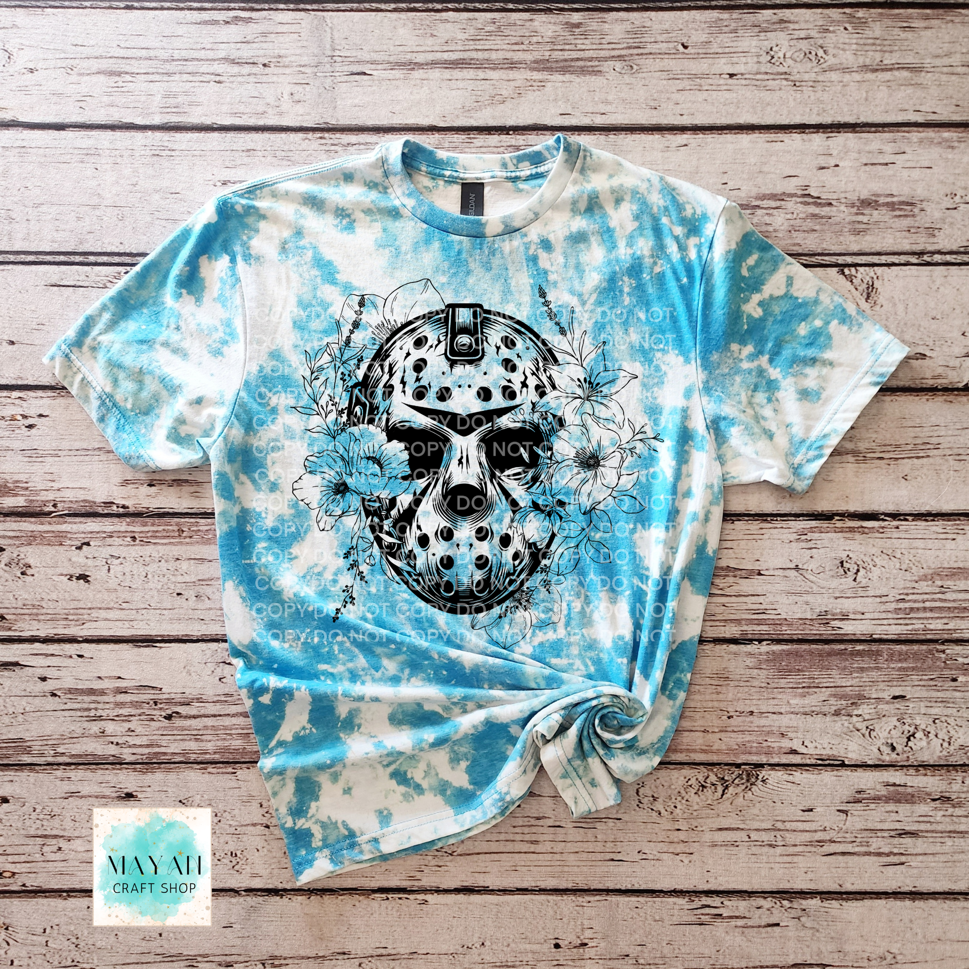 Tie-dye t-shirt with a black skull design on a wooden surface, featuring the brand 'Mayhem'.