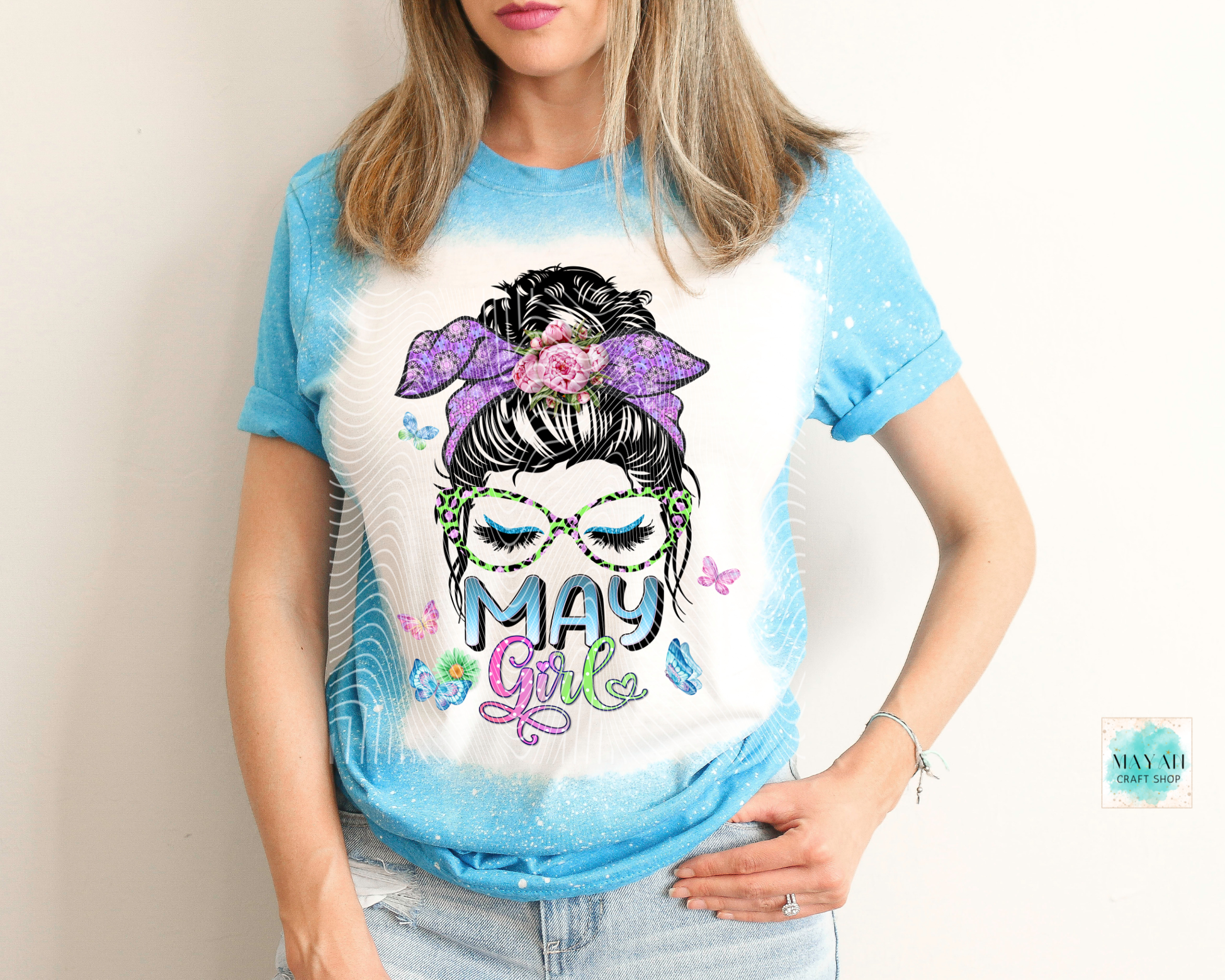 Person wearing a t-shirt with a graphic design and text 'May Girl' on a plain background