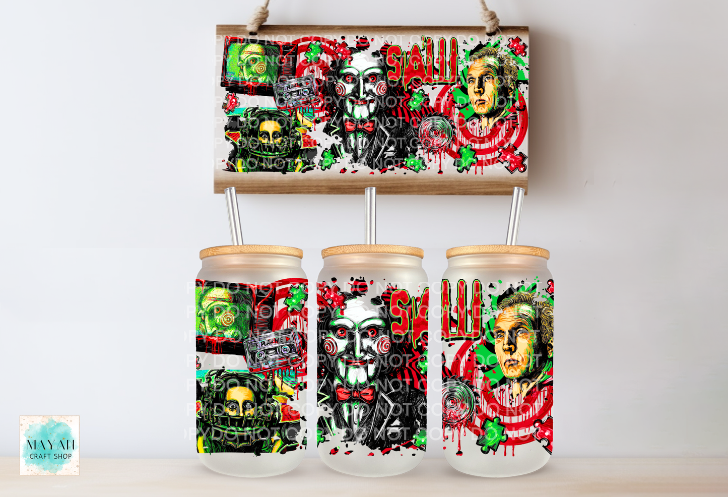 Three frosted glass can-shaped tumblers with bamboo lids and metal straws, displayed below a matching rectangular canvas print featuring a horror-themed collage with skulls, faces.