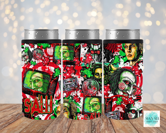 Three insulated can coolers with silver aluminum can tops, featuring a colorful horror-themed collage print of a face, cassette tapes, displayed on a wooden surface against a blurred bokeh background.