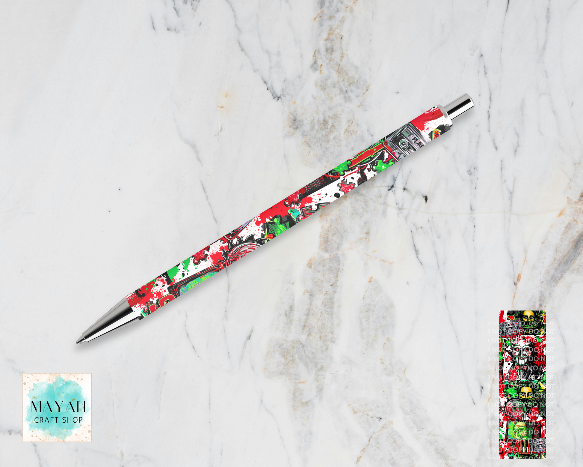 A novelty ballpoint pen with a colorful Halloween-themed pattern on a white marble background. A small inset image on the bottom-right shows the patterned end cap of the pen.
