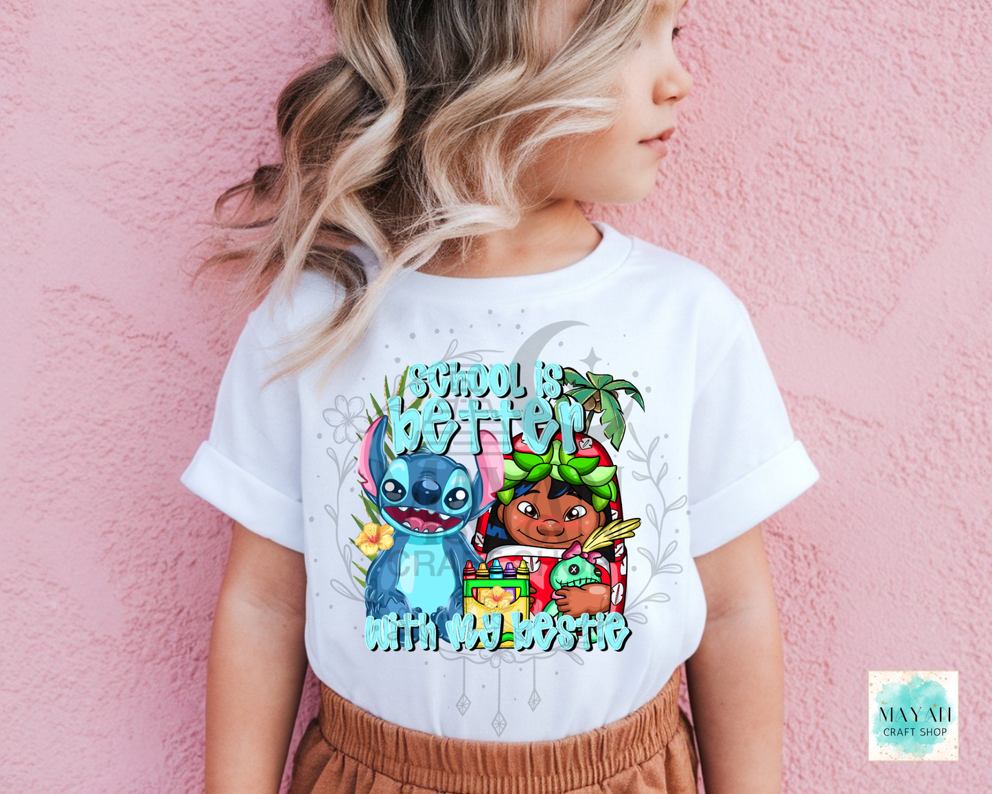 A child wearing a white graphic T-shirt featuring cartoon characters and the text 'SCHOOL IS BETTER WITH MY BESTIE' against a pink textured wall.