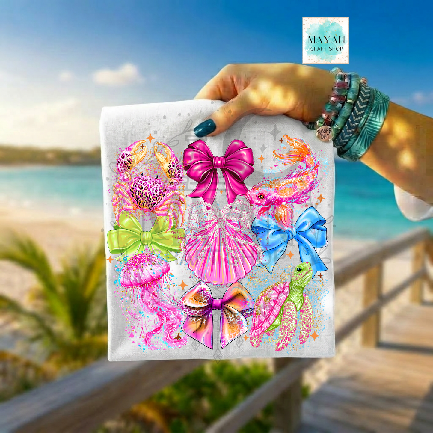 Hand holding a product with colorful designs against a beach background