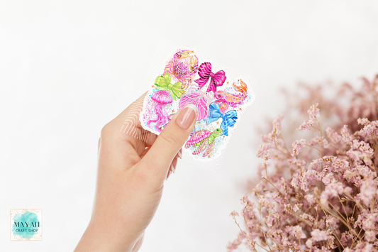 Hand holding a colorful sticker with dried pink flowers in the background