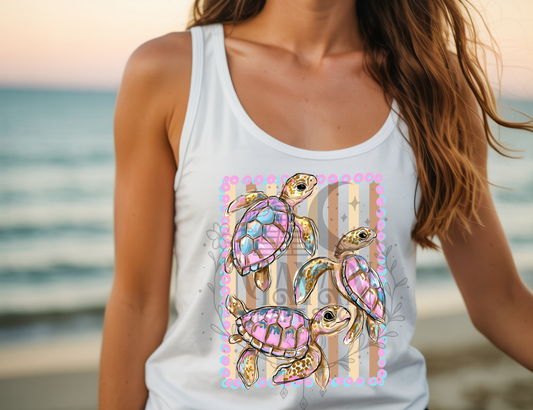Person wearing a white tank top with colorful turtle design on a beach.