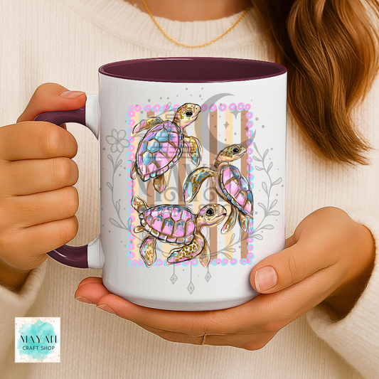 Person holding a mug with colorful turtle design.