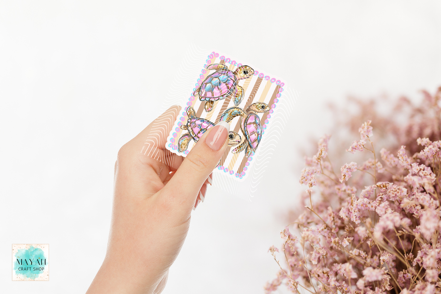 Hand holding a colorful sticker with pink flowers in the background