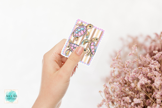 Hand holding a colorful sticker with pink flowers in the background