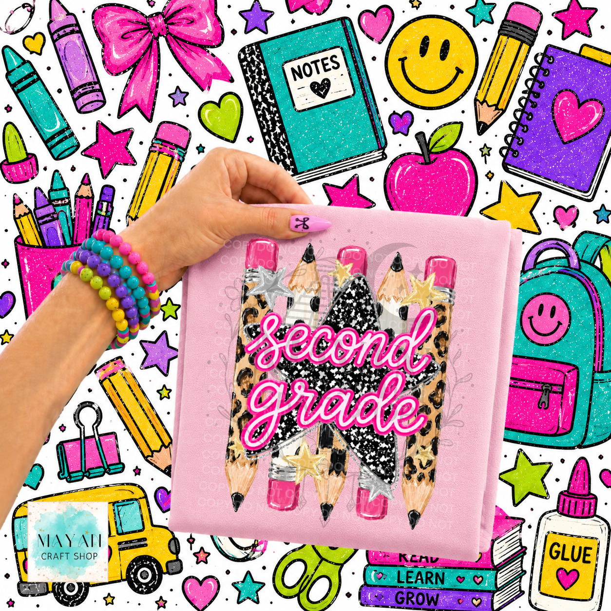 A hand holds a pink shirt with a graphic of three glitter pencils and the words 'Second Grade' in pink glitter script. The background is a busy, colorful doodle-style illustration filled with school supplies, stars, smiley faces, and bright colors.