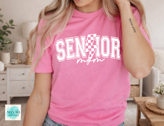 Person wearing a pink t-shirt with 'Senior Mom' text in a home setting