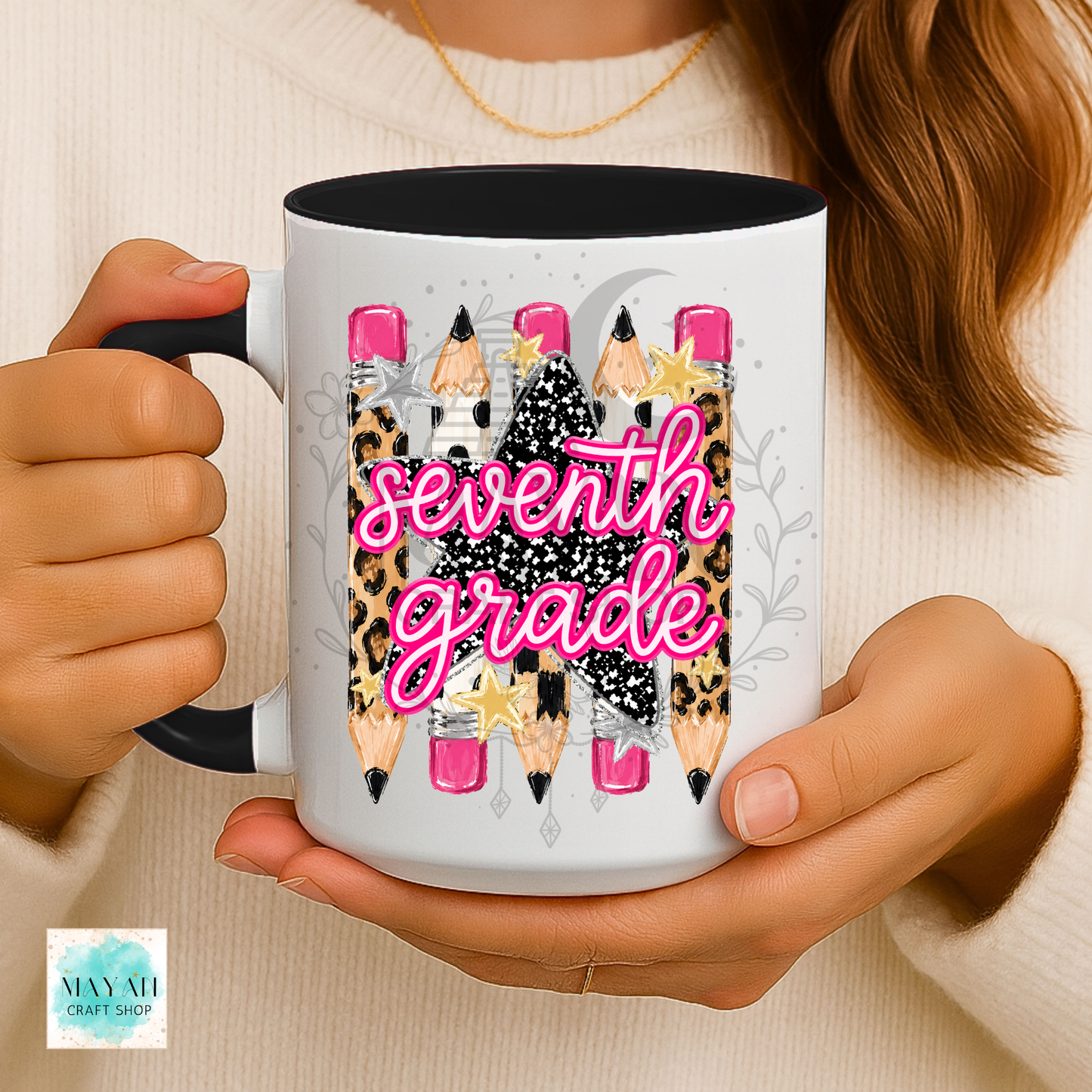 A person holds a white ceramic mug with a black handle and interior. The mug features a graphic design of pencils with leopard print, black glitter textures, pink tips, and the word 'pre-k' in bright pink script.