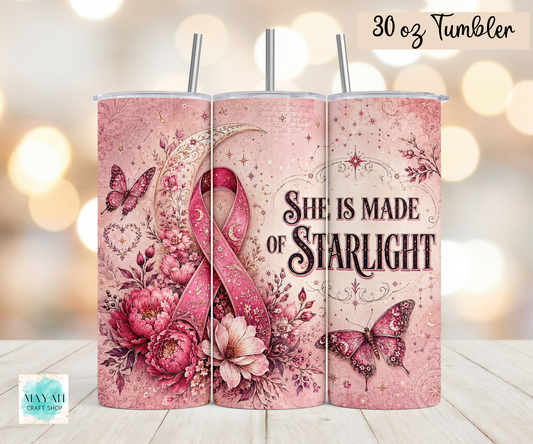 Three views of a 30 oz stainless steel tumbler with a pink floral and ribbon design, featuring the text 'She Is Made Of Starlight' and butterflies, shown on a wooden surface with a warm bokeh background.