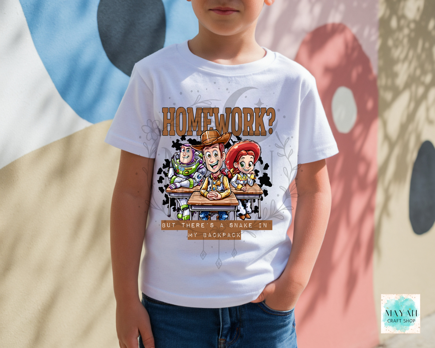 A child wearing a white graphic t-shirt featuring the 'Homework?' character design from a cartoon character, paired with blue jeans, standing outdoors against a painted wall.