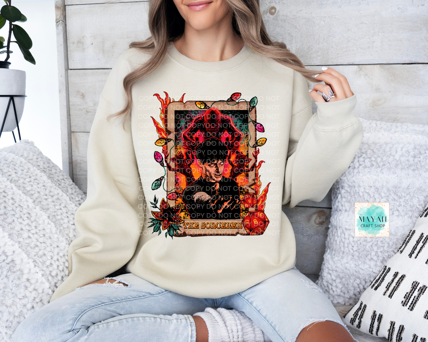 Person wearing a cream sweatshirt with a graphic design sitting on a couch.