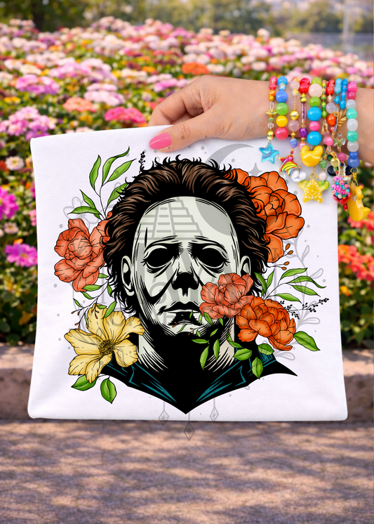 Hand holding a shirt of a face with floral elements against a colorful flower background.