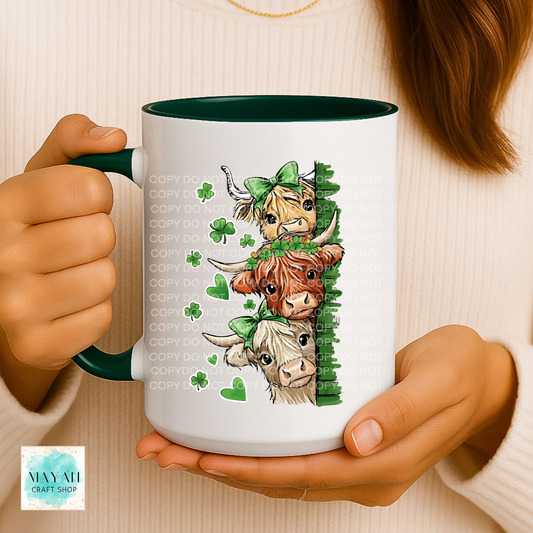 Person holding a mug with cartoon cows and shamrocks design