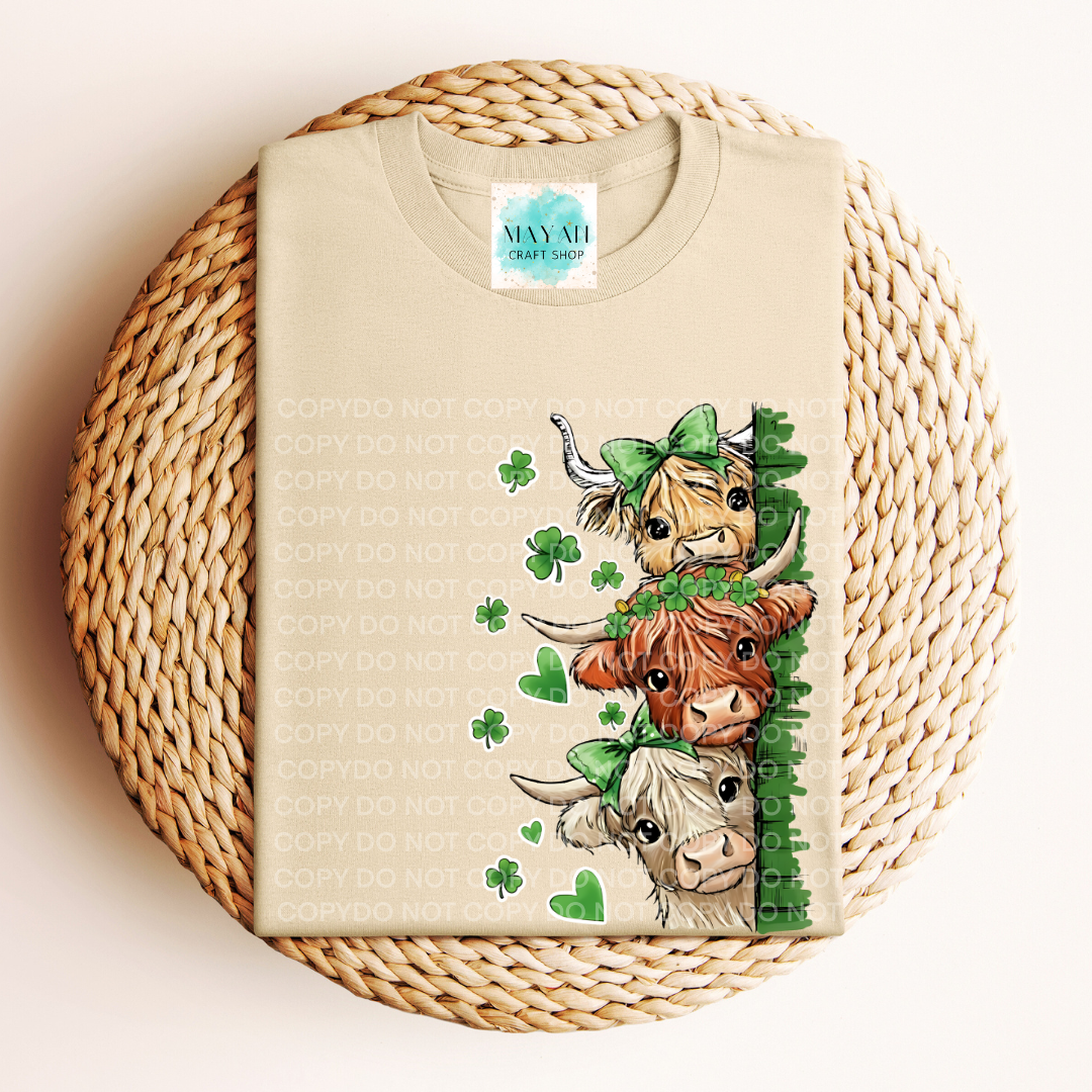 Beige t-shirt with highland cow design on a woven surface