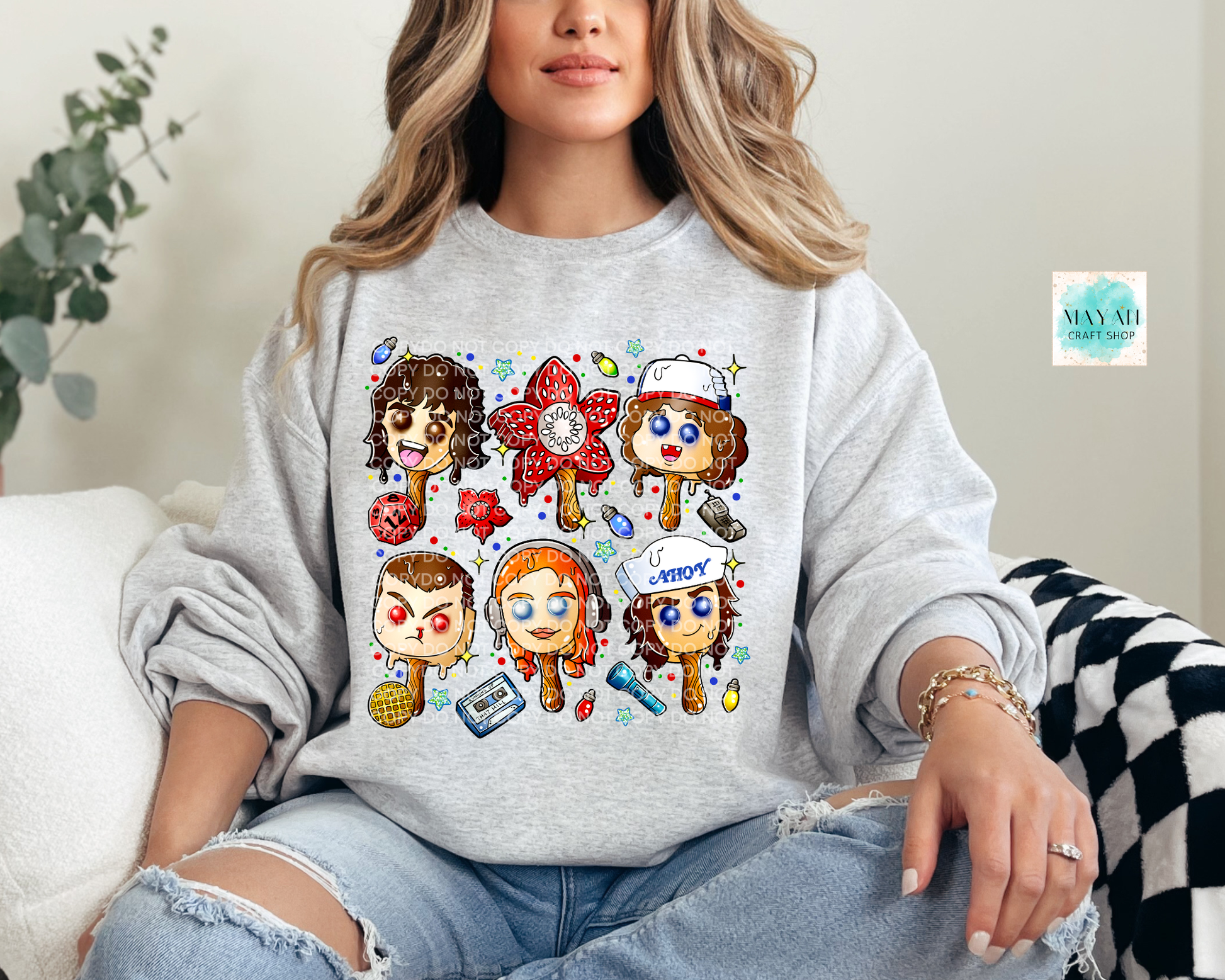 Person wearing a gray sweatshirt with cartoon character designs sitting on a couch.