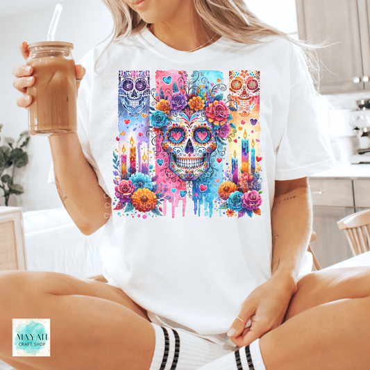 Person wearing a white t-shirt with a colorful skull design, holding a drink.