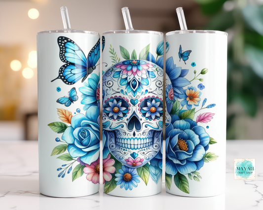 Three tumblers with colorful designs of a skull, flowers, and butterflies on a blurred background.