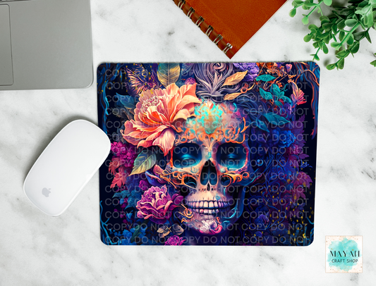 Colorful skull and floral design mouse pad on a marble surface with a laptop and mouse.