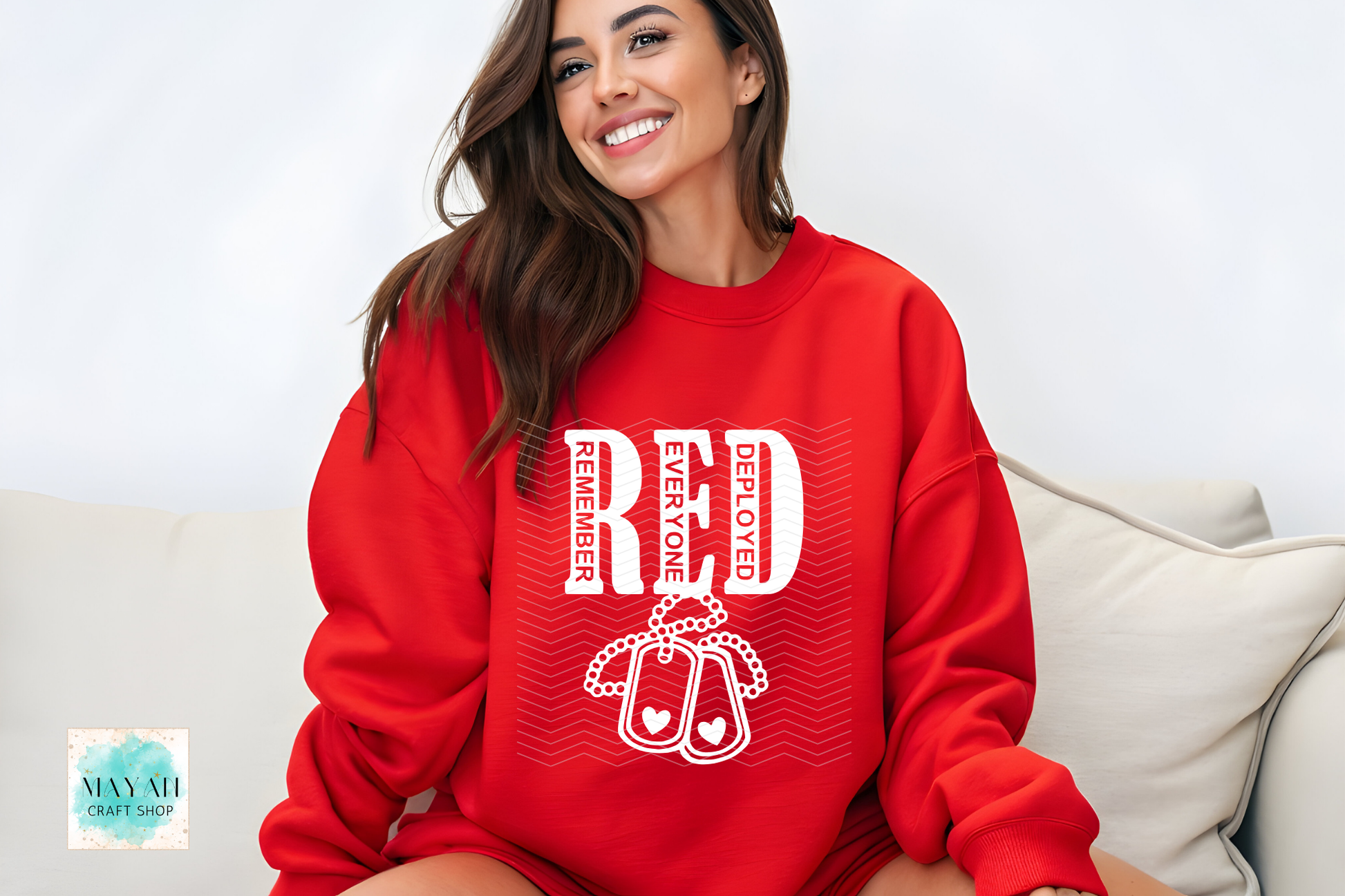 Woman wearing a red sweatshirt with white text and graphics, sitting on a couch.